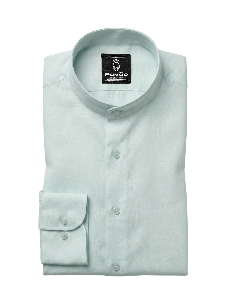 A folded light mint green dress shirt with a band collar and a single-button cuff, displayed on a neutral light gray background. The brand label 'Pavão' is visible inside the collar.