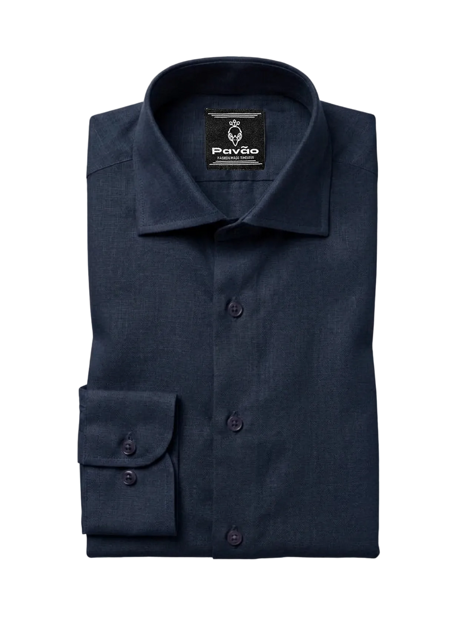 A folded navy blue dress shirt with a spread collar and a single cuff, displayed on a light gray background. The brand label 'Pavão' is visible inside the collar.